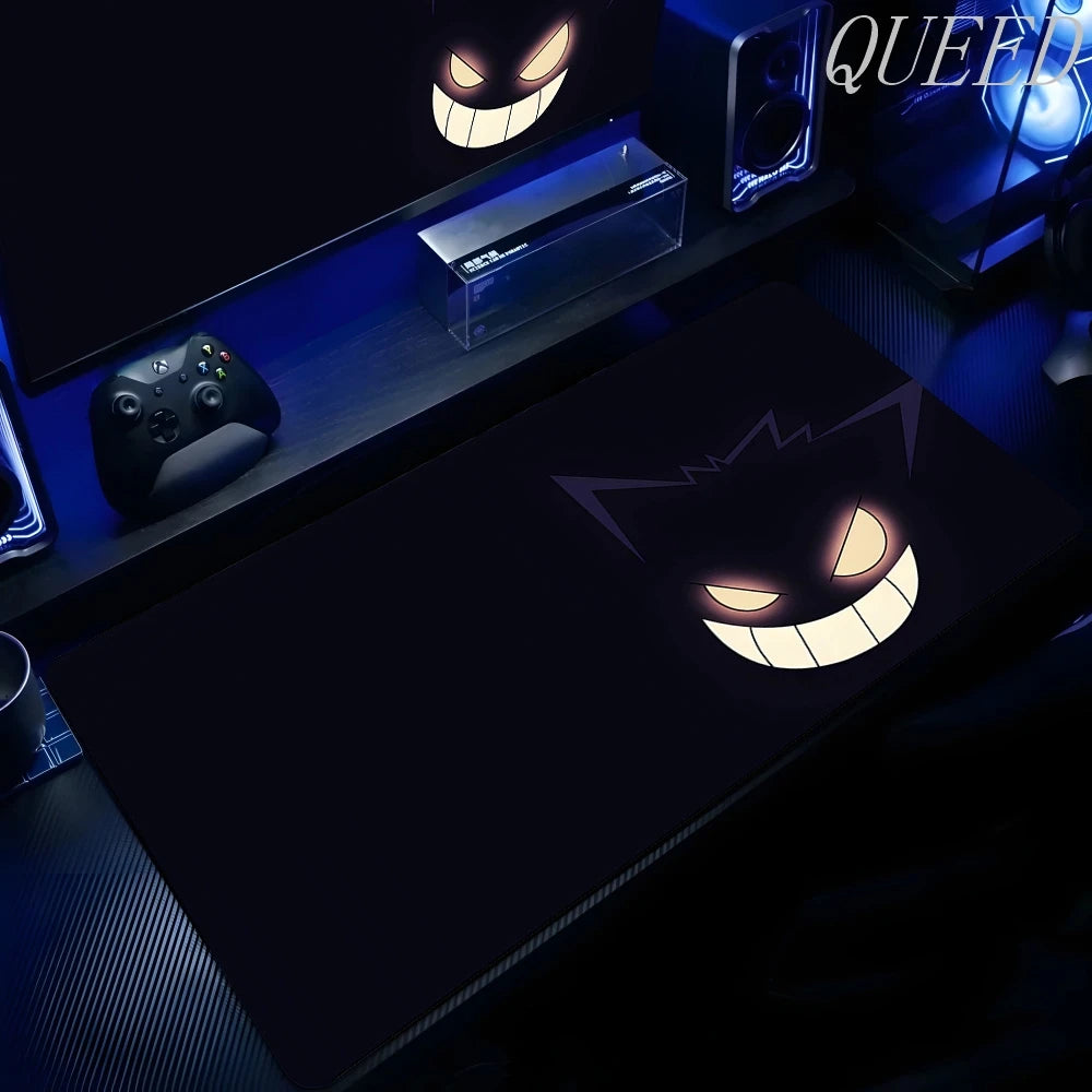 Black XXL gaming mouse pad featuring Gengar's glowing yellow eyes and wide smile in a blue-lit setup.