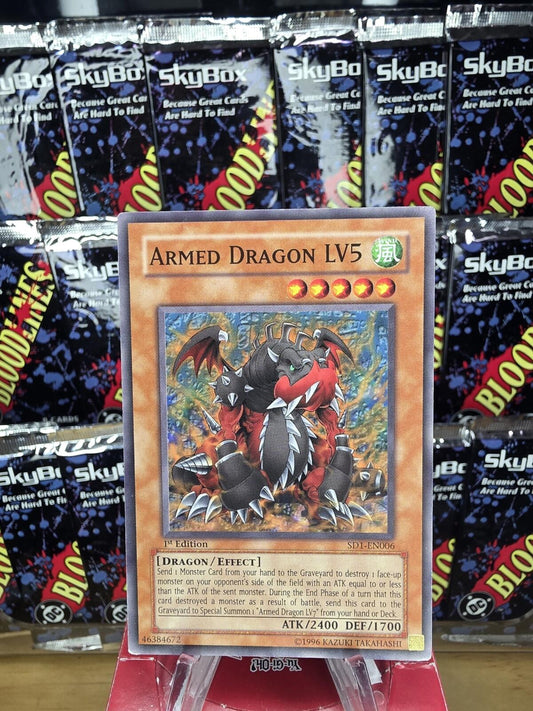Armed Dragon LV5 1st Edition card in orange and red, depicting a spiked black and red monster.