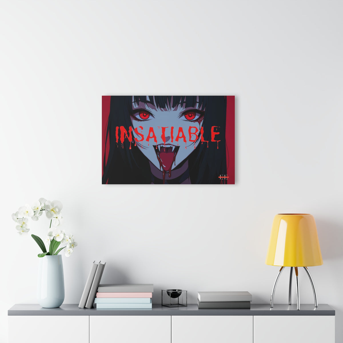 "INSATIABLE" anime vampire acrylic artwork hanging on a white wall above a shelf with books, flowers, and a yellow lamp.