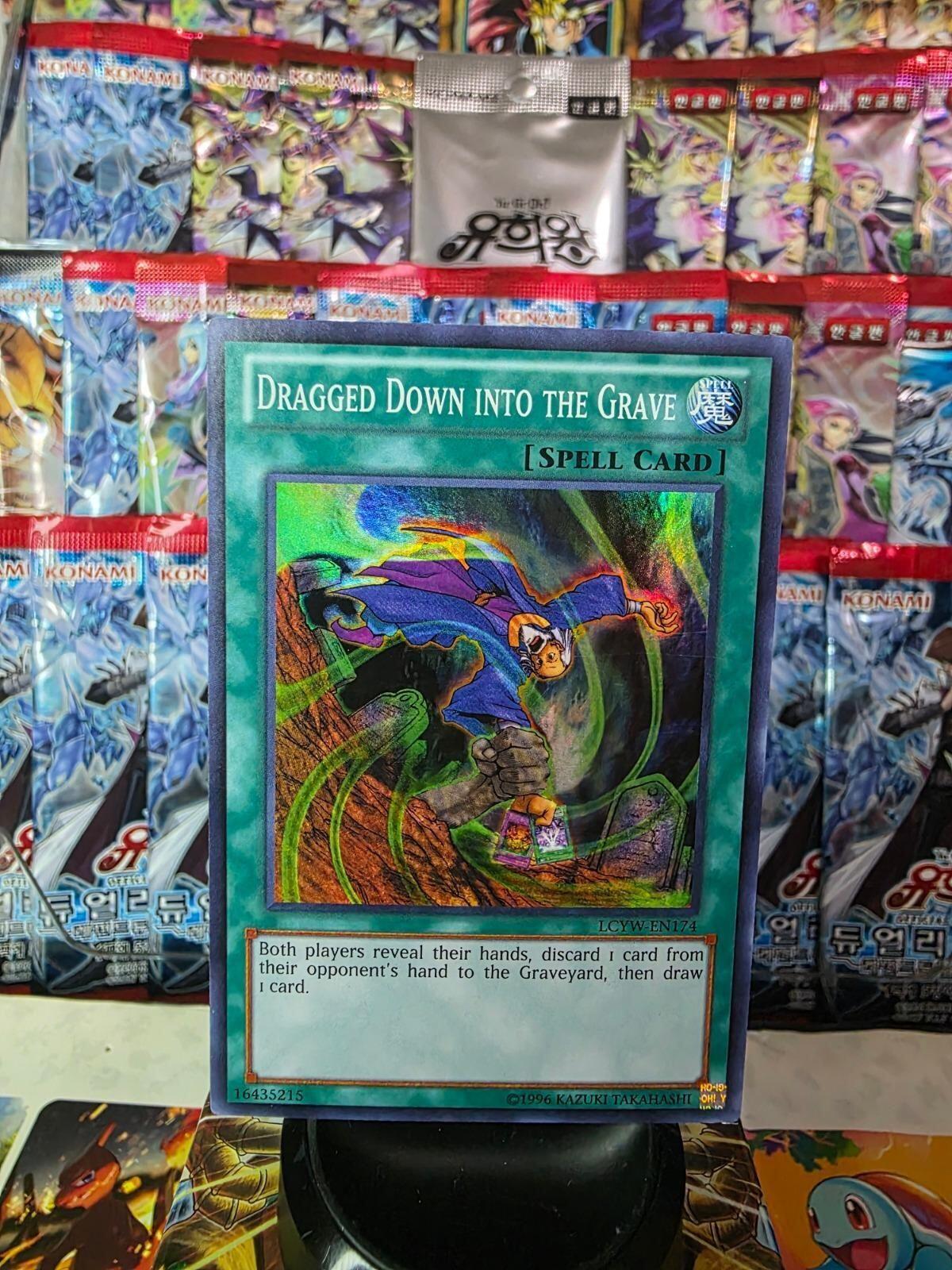 Dragged Down into the Grave Super Rare Yu-Gi-Oh! spell card with holographic foil in front of booster packs.