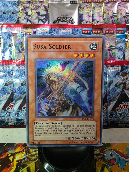 Susa Soldier Yu-Gi-Oh! card featuring shiny foil artwork against a background of booster packs.
