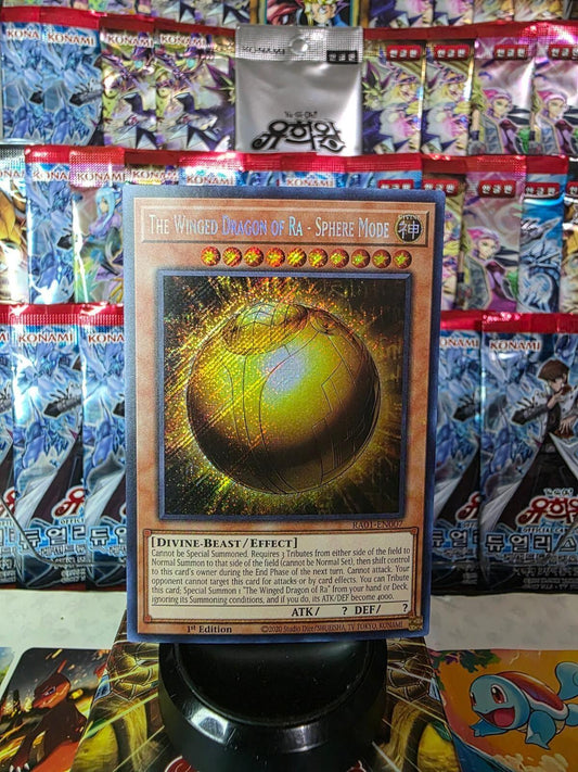 The Winged Dragon of Ra - Sphere Mode Secret Rare card on a stand with booster packs.