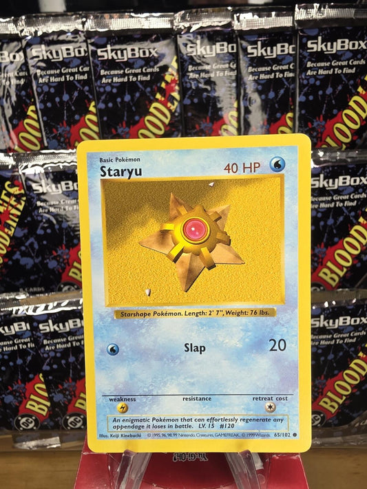 Vintage yellow and blue Staryu Pokémon card in front of SkyBox card packs.