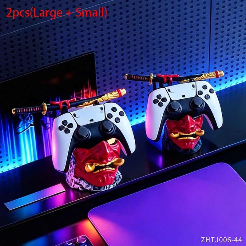 Two red and gold oni mask stands hold white and black game controllers with miniature samurai swords.