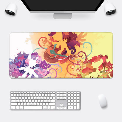 An XXL desk mat with abstract watercolor splashes in yellow, purple, and red, featuring silhouette pony characters.