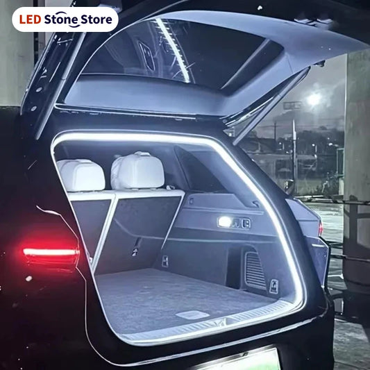 A white flexible LED strip illuminates the open trunk of a black SUV at night.