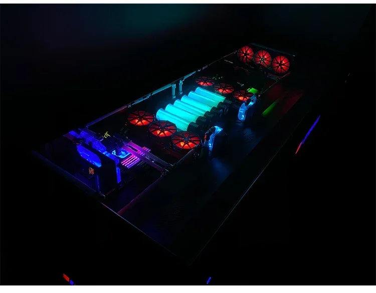 An integrated desk computer chassis glowing with red, blue, and bright green RGB lights in a dark room.