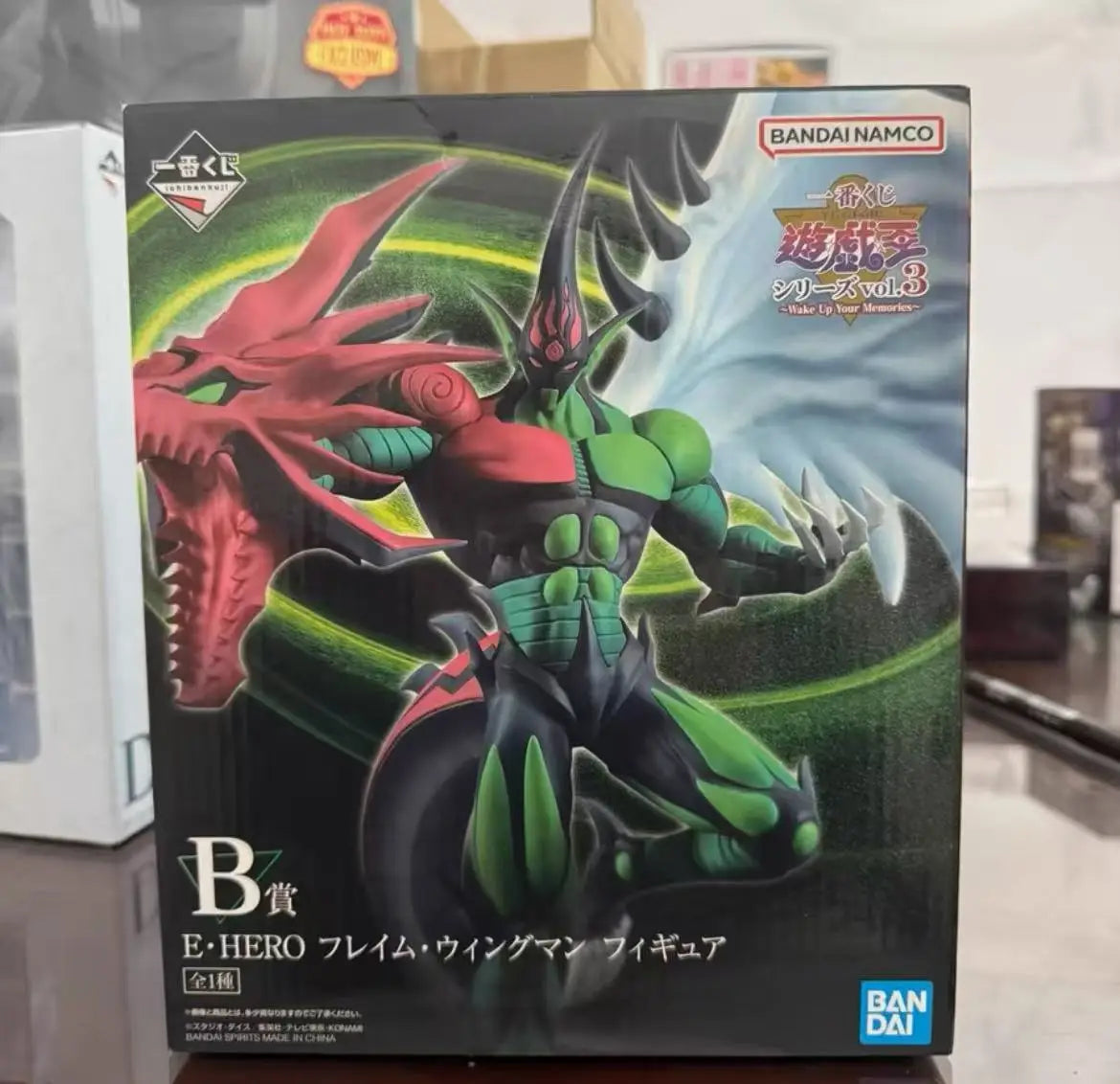 Box for E·HERO Flame Wingman figure featuring green and black colors with a large red dragon arm.