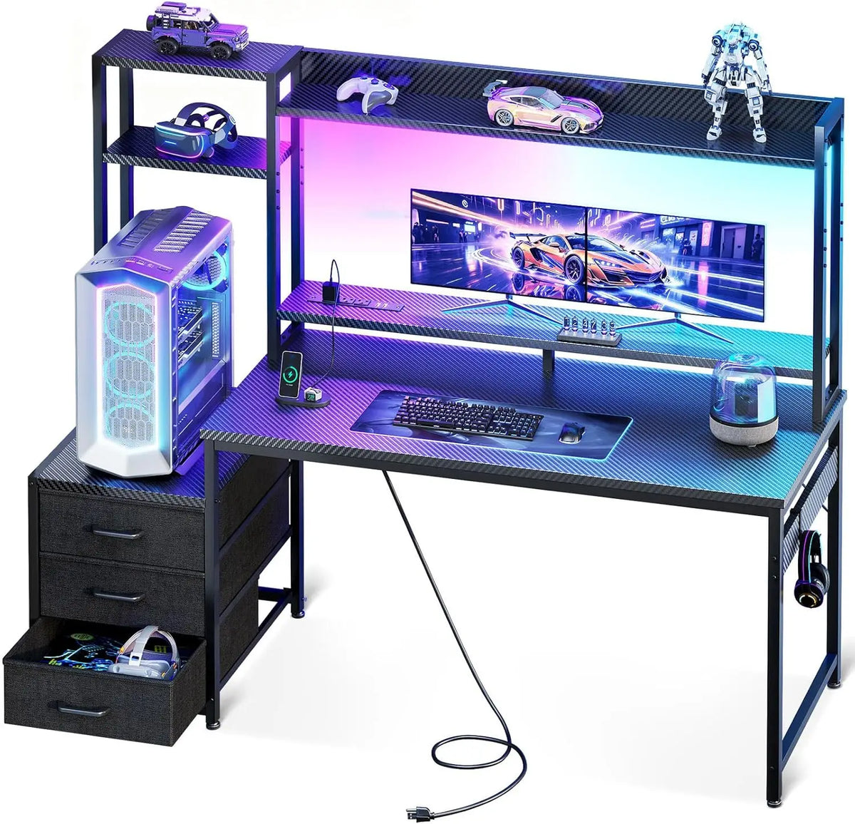 Black gaming desk with carbon-fiber texture, hutch, 3 fabric drawers, RGB lights, monitor, PC tower, and accessories.