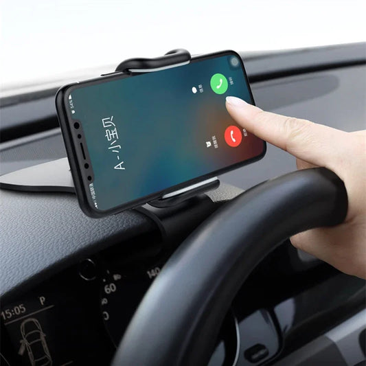 A black car phone holder clipped to the dashboard, holding a smartphone with an incoming call displayed.