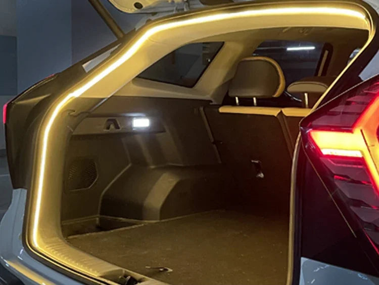 A bright LED strip light is installed around the open trunk frame of a car, illuminating the interior cargo area.