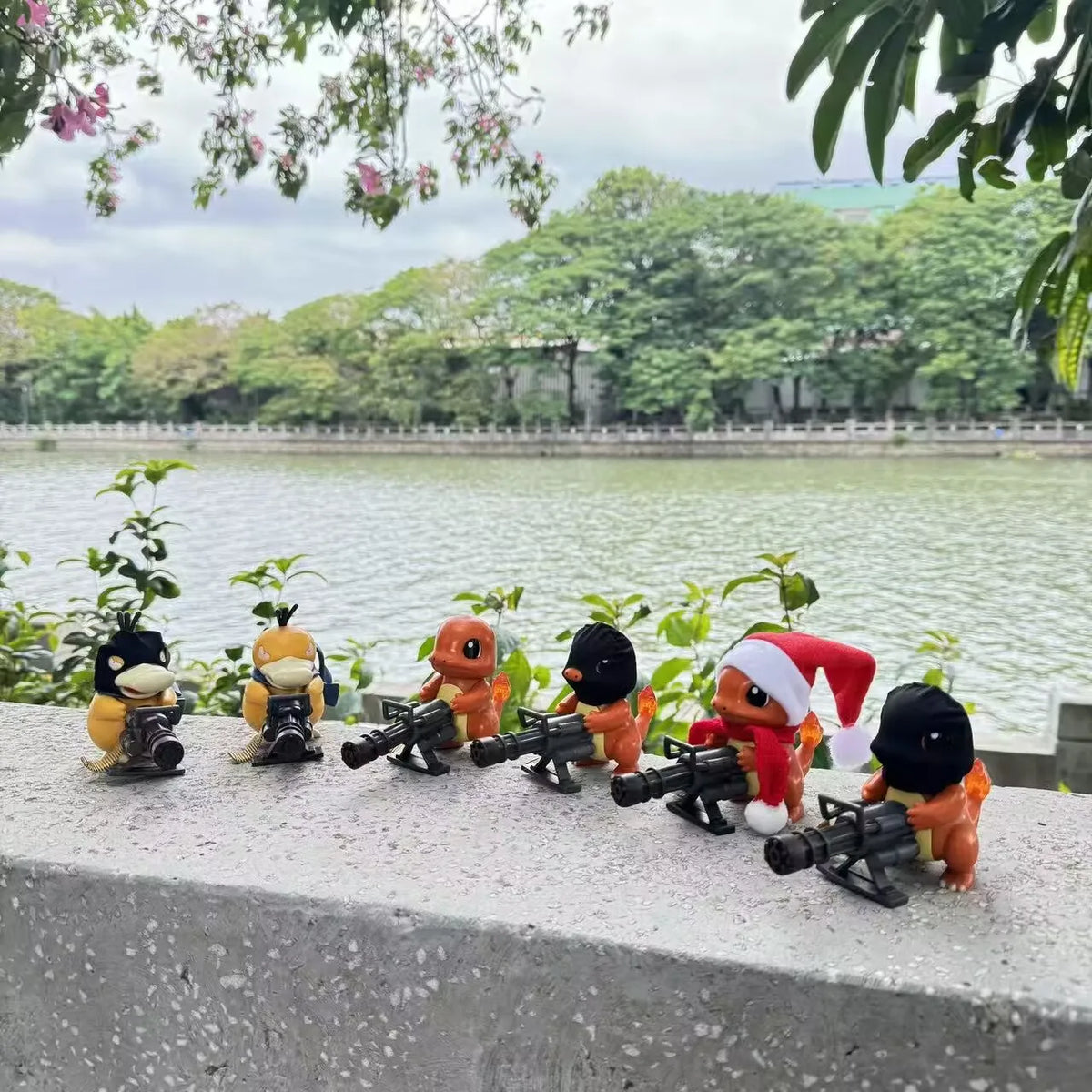Six small Pokémon figurines in ski masks and a Santa hat, holding Gatling guns outdoors.