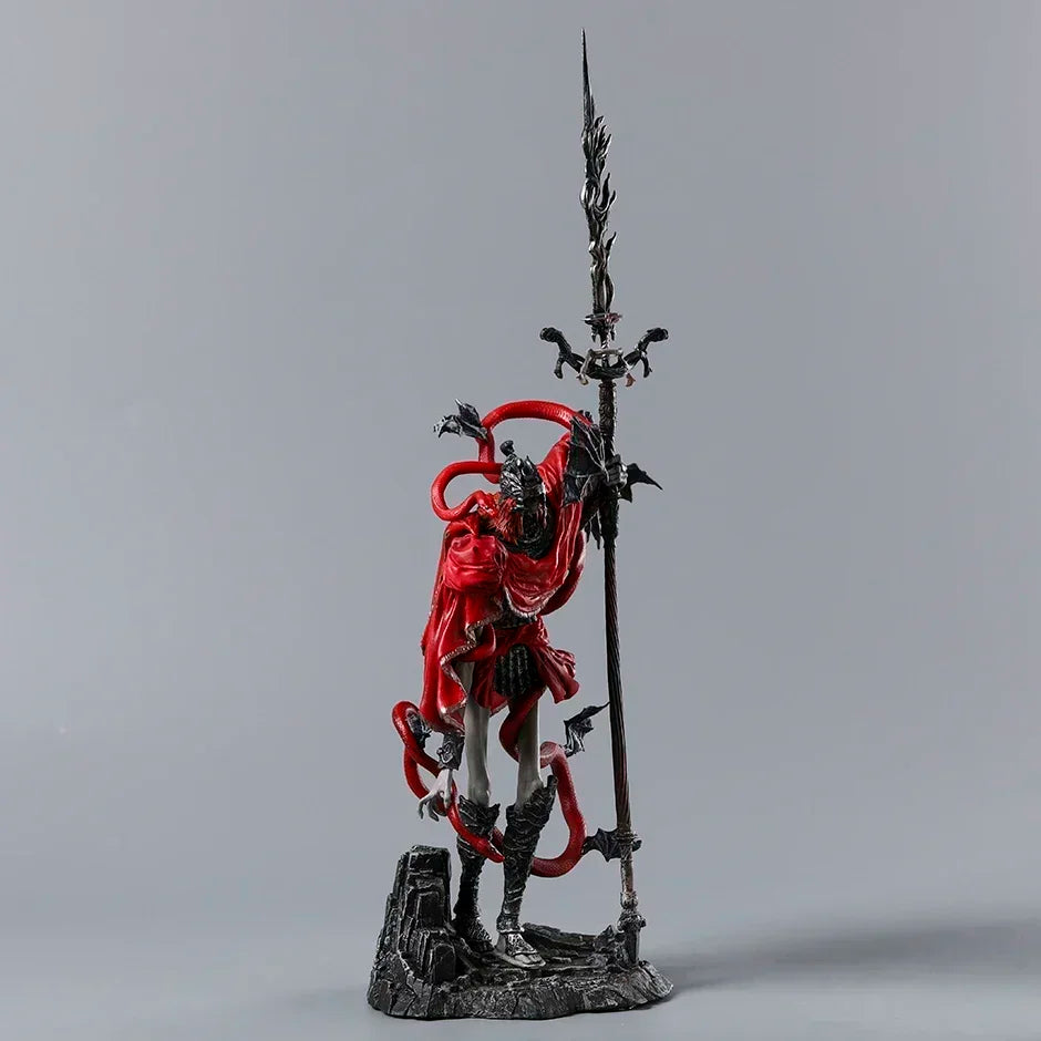 PVC figurine of a humanoid character in a red cloak, holding a tall spear, standing on a rocky base.