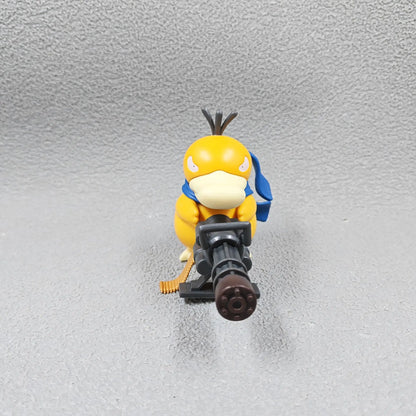 A yellow Psyduck figurine holds a large grey gatling gun with an ammo belt, wearing a blue scarf.