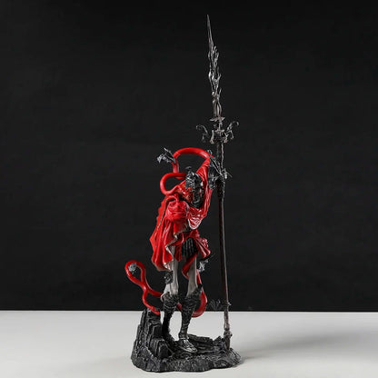 Gray-skinned PVC figurine in a red cloak, holding a tall spear, standing on a rocky base against a black background.