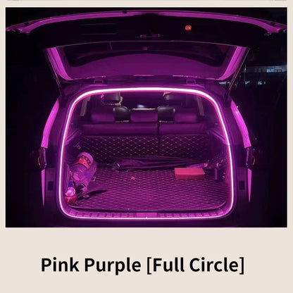 A car trunk interior illuminated by a continuous glowing pink-purple LED light strip tracing the open frame.