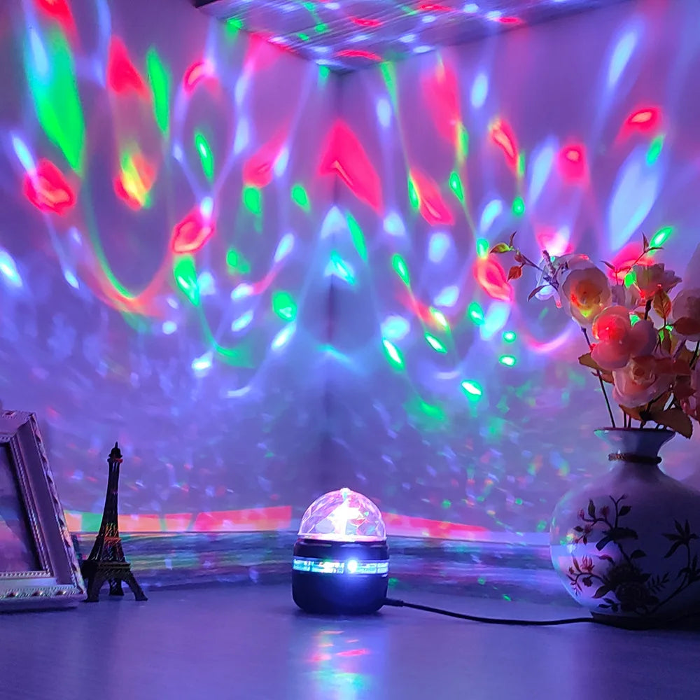 A small dome-shaped LED projector casts red, green, and blue light patterns across a white wall and ceiling.
