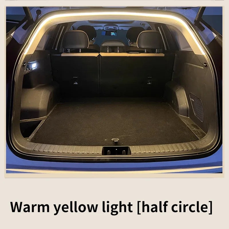 A car trunk illuminated by a curved LED light strip along the upper frame, casting a warm yellow glow.