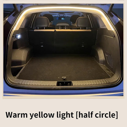 A car trunk illuminated by a curved LED light strip along the upper frame, casting a warm yellow glow.