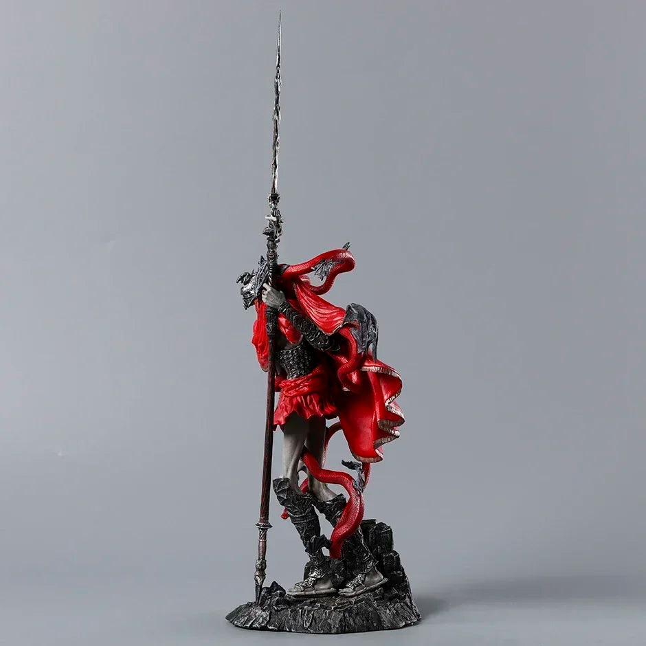 A PVC figurine in dark armor and a flowing red cape, holding a tall, pointed spear.