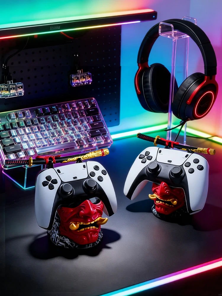 Two red Oni mask resin stands hold white gaming controllers with miniature samurai swords on top.