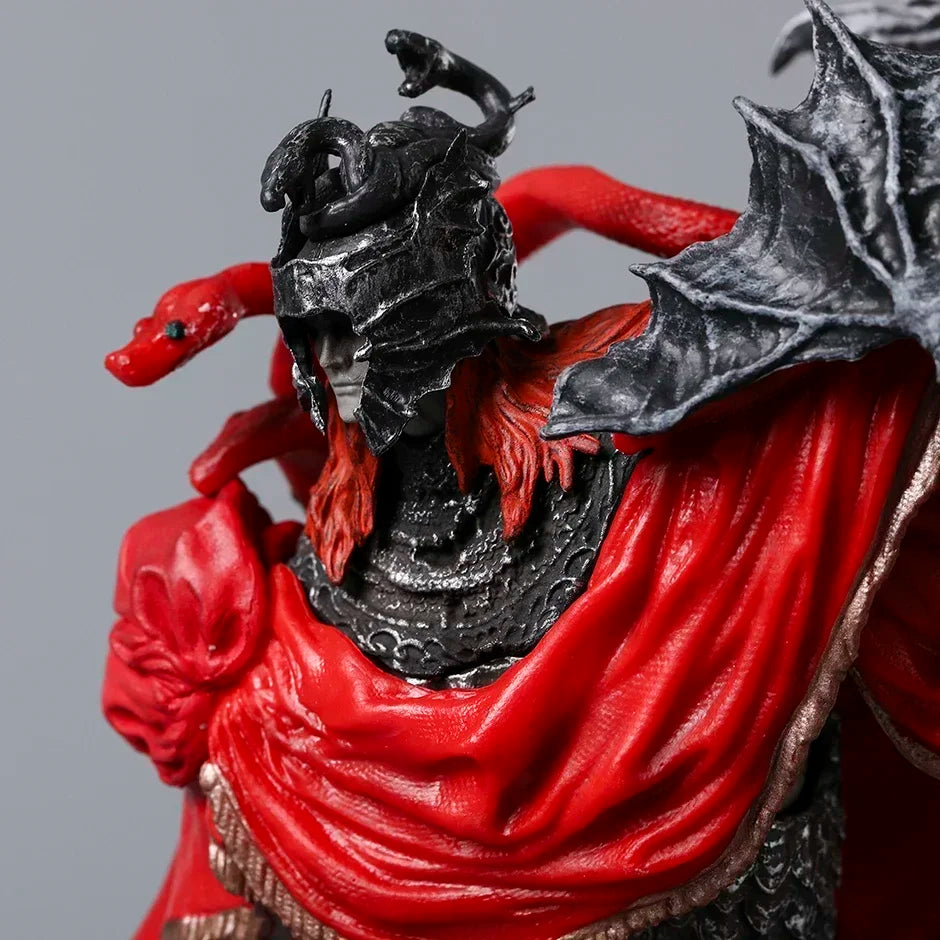 A PVC figurine wears a dark, ornate helmet with snakes, a red cape, and black armor with red hair framing the pale face.