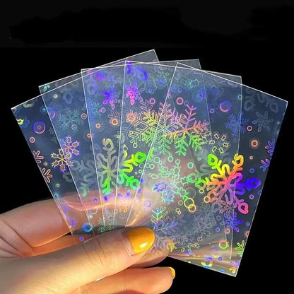Fanned transparent card sleeves with a holographic rainbow laser foil snowflake and circle pattern.