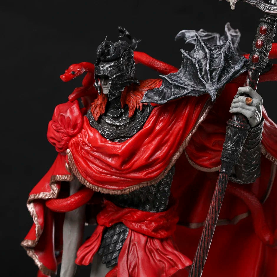 A detailed PVC figurine in dark armor, red cape, and helmet with a red snake, holding a staff.