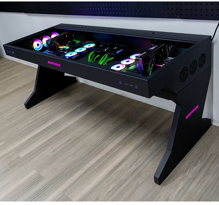 A black desk with a glass top housing two computer setups, featuring glowing RGB fans and components.