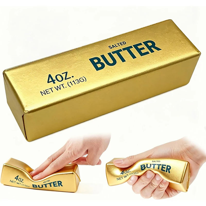 A golden butter stick stress toy labeled "SALTED BUTTER 4oz. NET WT." being squeezed by hands.