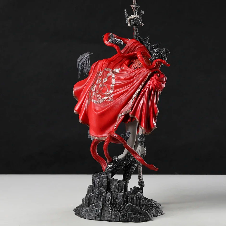 A PVC figurine in a red hooded cloak with a red snake wrapped around it, standing on a rocky base.