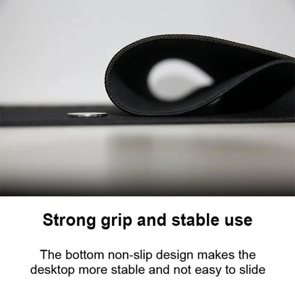 Black mousepad rolled up, showing a stitched locking edge, textured non-slip underside, and a coin on the surface.