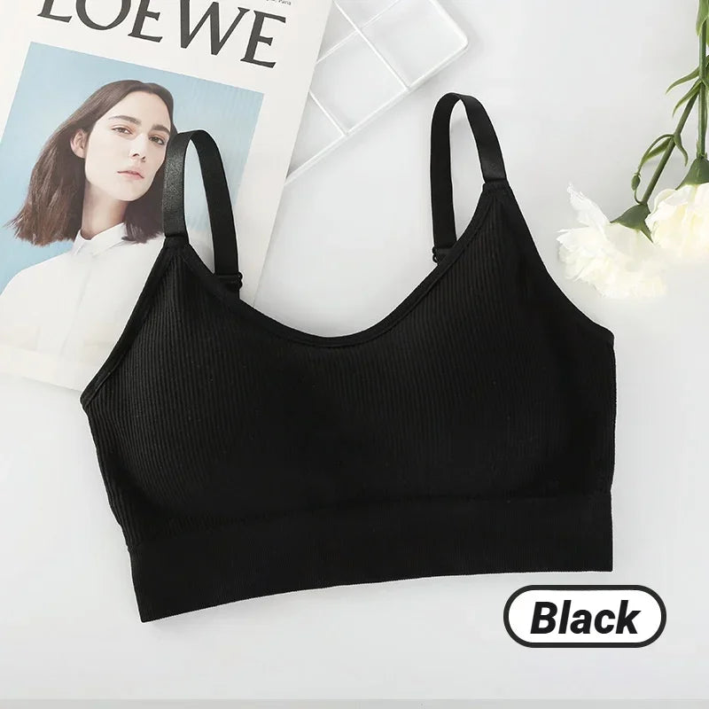 A black ribbed seamless bralette with thin straps rests on a surface alongside a magazine, white flower, and "Black" label.