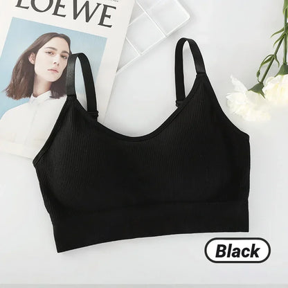 A black ribbed seamless bralette with thin straps rests on a surface alongside a magazine, white flower, and "Black" label.