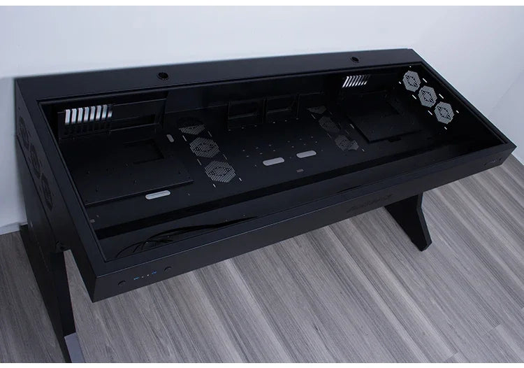 Large black metal computer chassis desk with integrated dual host compartments, vents, and fans on grey wood floor.