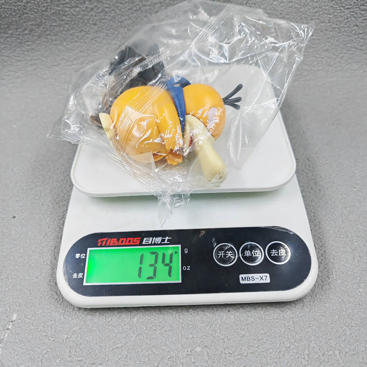 A yellow figure in a plastic bag on a digital scale reading 134g.