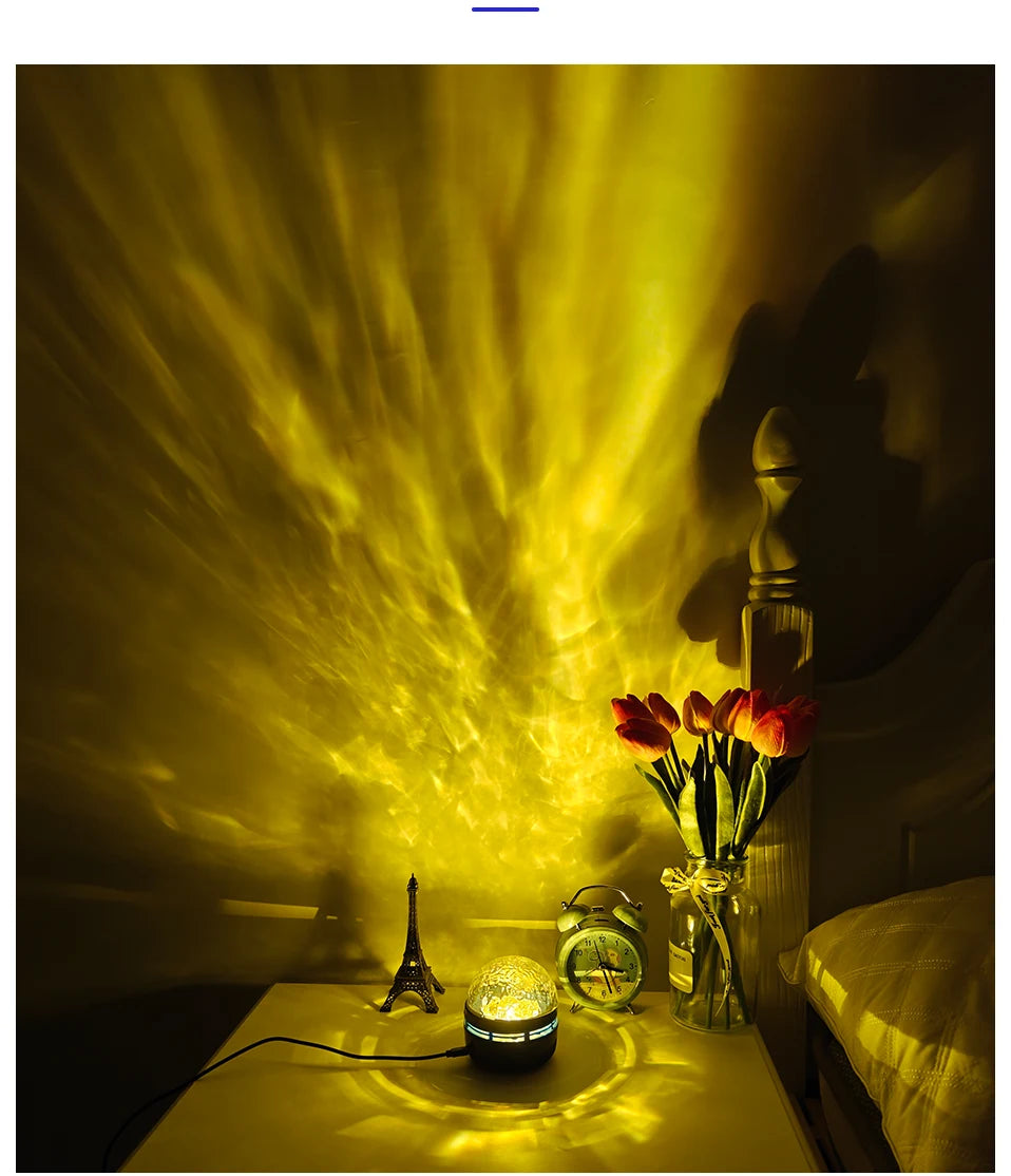 A galaxy projector lamp on a nightstand projects yellow rippling light onto a wall, illuminating a bedside clock, flowers, and decor.