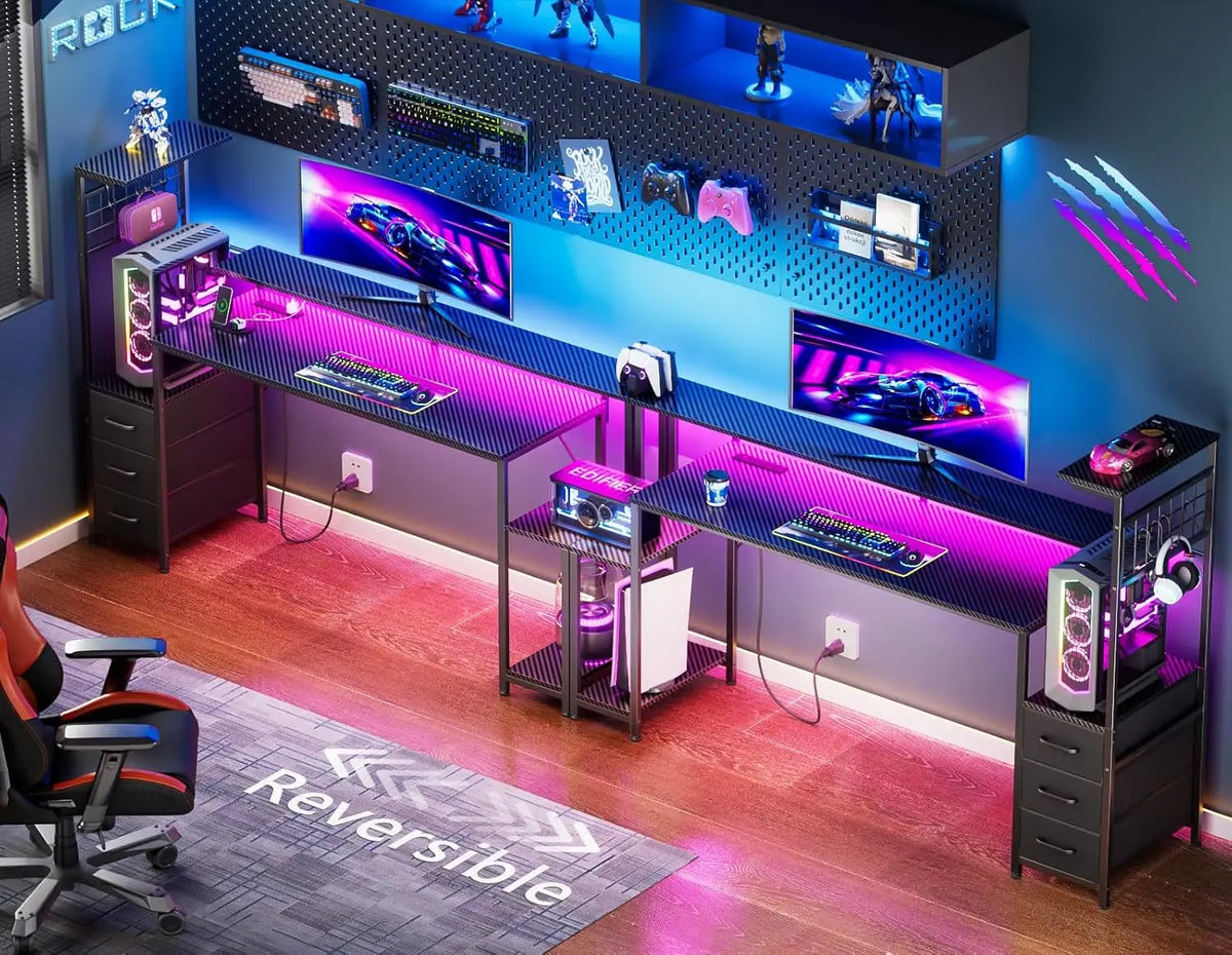 Dual black carbon-fiber gaming desks with pink LED backlighting, monitors, keyboards, drawers, and upper shelving units.
