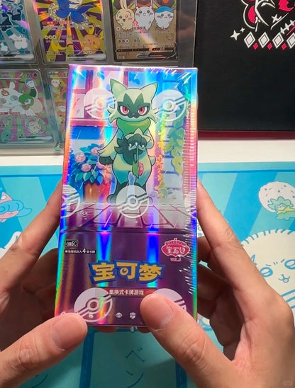 Hands holding a shiny, foil-wrapped Pokémon booster box featuring Sprigatito and Chinese text.