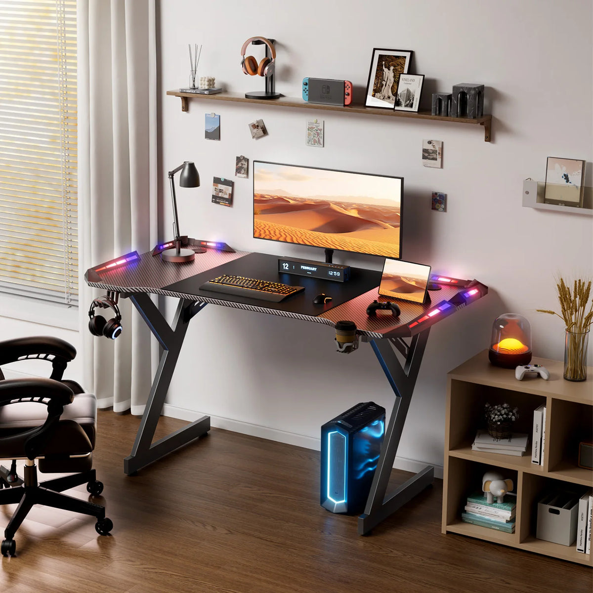 Black Y-shaped gaming desk with RGB LED lights on the surface, supporting a monitor, keyboard, and mouse.