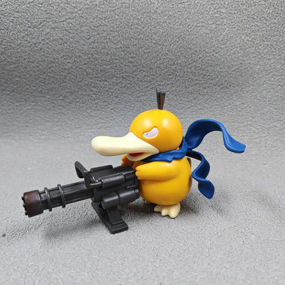 Yellow duck-like figurine with a blue scarf, holding a large black Gatling gun.