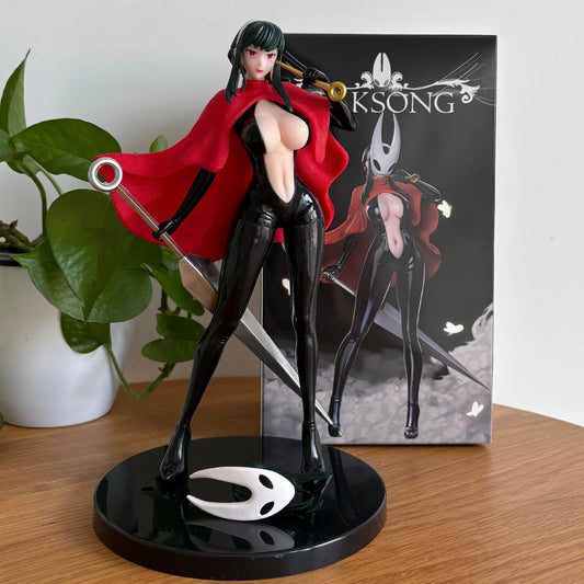 A figurine of a female character with a red cloak and black suit, holding a needle weapon, with a white mask nearby.