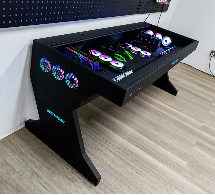 A large black computer desk houses integrated PC components under glass, featuring colorful RGB cooling fans.