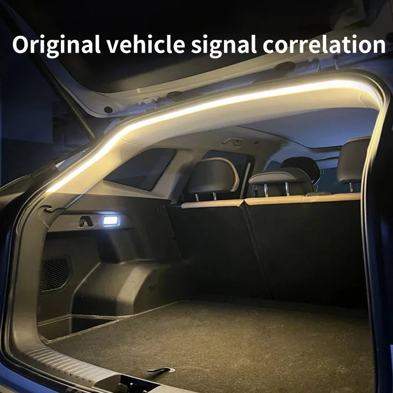 A bright white LED light strip is installed along the top edge of an open car trunk, illuminating the interior.