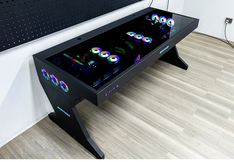 Black computer desk with a glass top, showcasing integrated PC components and glowing RGB fans.