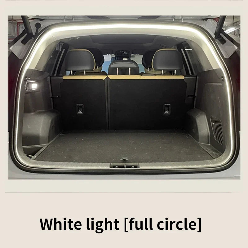 A bright white LED light strip frames the open trunk opening of a vehicle, illuminating the dark interior.