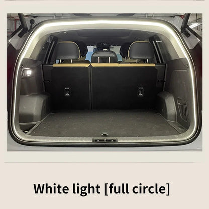 A bright white LED light strip frames the open trunk opening of a vehicle, illuminating the dark interior.