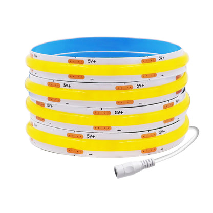 A rolled yellow COB LED strip light with a white power connector on a white background.