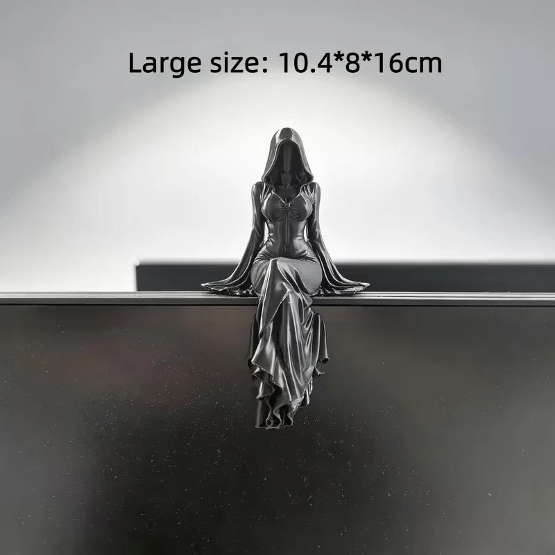 Black, hooded female figurine sitting on a ledge with flowing dress and draped sleeves.