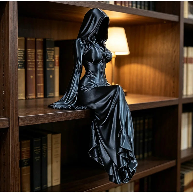 A black, hooded female figure statue sits on a wooden shelf, her long dress draping over the edge.